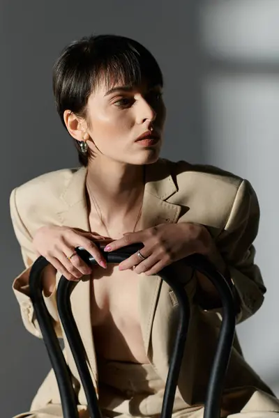 A woman with short dark hair sits on a chair, looking away from the camera. — Stock Photo