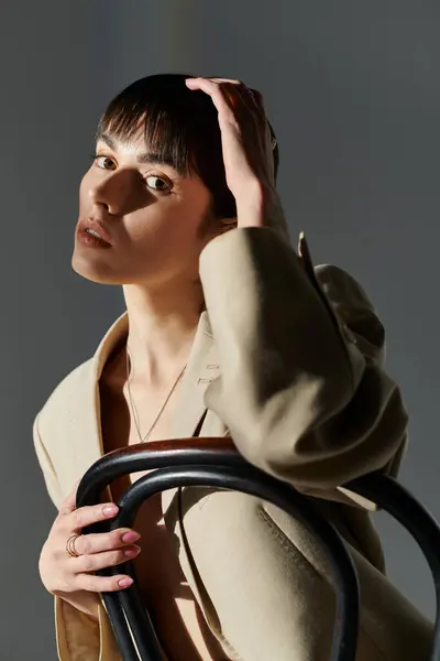A young woman poses, hand resting on her head, against a backdrop of soft light. — Stock Photo