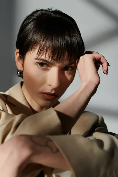 Porträt einer Frau mit kurzen, dunklen Haaren, die in einer beigen Jacke mit einem subtilen Lächeln posiert. — Stockfoto