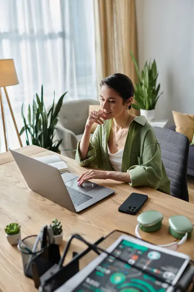 A woman sits at a desk in her home office, working on her laptop. — Stock Photo