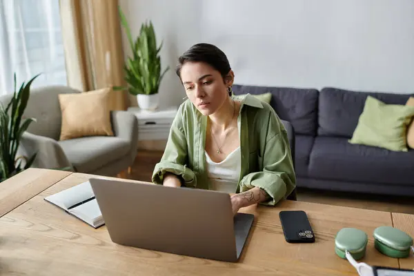 A woman sits at a table in her home, working on a laptop. — Stock Photo
