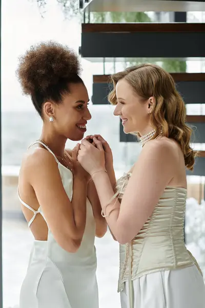Una pareja de lesbianas se da la mano con amor el día de su boda. - foto de stock