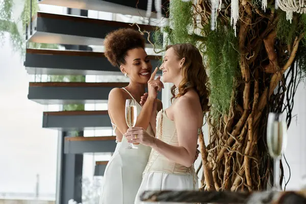 Two brides in white dresses celebrate their wedding with a playful moment. — Stock Photo