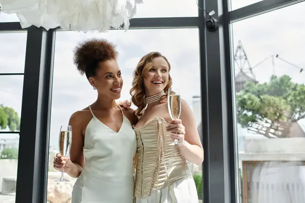 Duas mulheres em vestidos brancos brindam com champanhe em seu casamento. — Fotografia de Stock