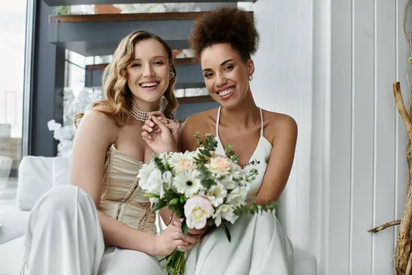 Two brides, wearing white dresses, pose for a wedding photo. — Stock Photo