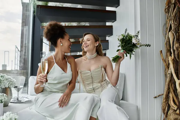 Zwei Bräute feiern ihre Hochzeit mit einem Glas Champagner und einem Blumenstrauß. — Stockfoto