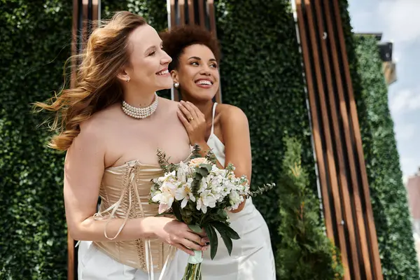 Duas noivas sorriem uma para a outra durante a cerimônia de casamento. — Fotografia de Stock