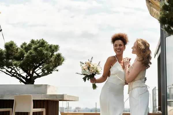 A happy lesbian couple celebrates their wedding day on a rooftop terrace. — Stock Photo
