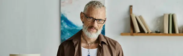 A mature, tattooed gay man with grey hair works remotely from home, exuding confidence and style. — Stock Photo