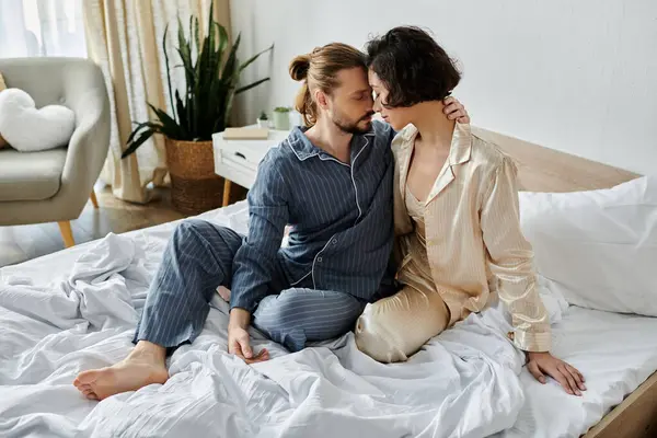 Un couple en pyjama se blottit sur un lit, profitant d'un moment paisible ensemble. — Photo de stock