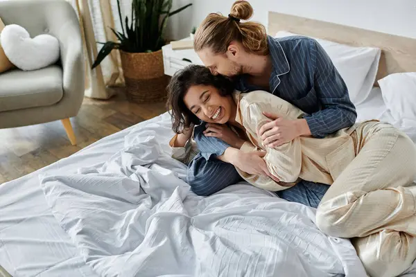 A couple shares a loving moment in bed, laughing and embracing. — Stock Photo