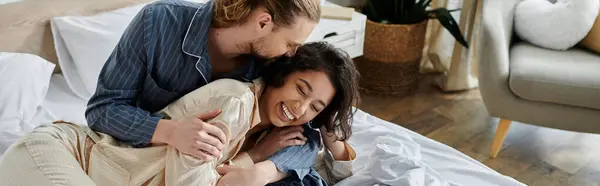 A couple enjoys a playful moment in their home, the man kissing his partner while she laughs. — Stock Photo