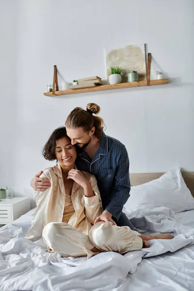 A couple in pajamas embraces on the bed, enjoying a quiet moment together. — Stock Photo