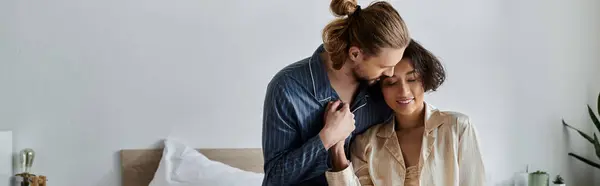 Una pareja en pijama comparte un momento tierno en su dormitorio. - foto de stock