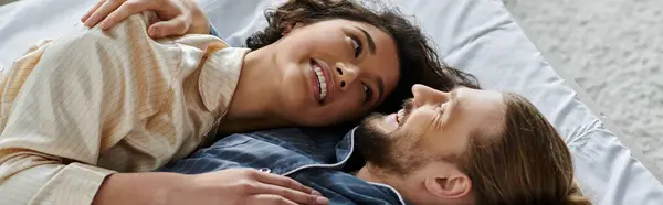 A loving couple cuddles on a bed, sharing a tender moment at home. — Stock Photo