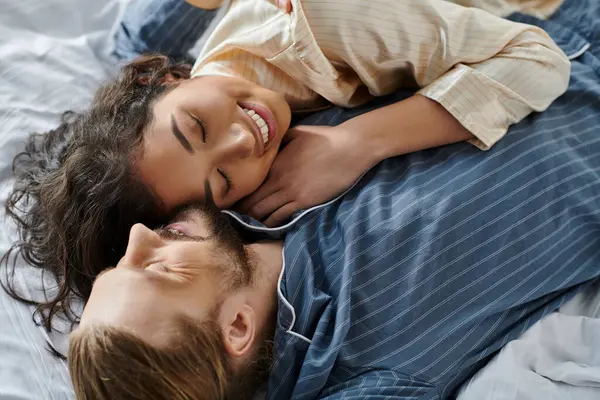 A loving couple embraces and rests on a bed, enjoying a cozy and intimate moment together. — Stock Photo