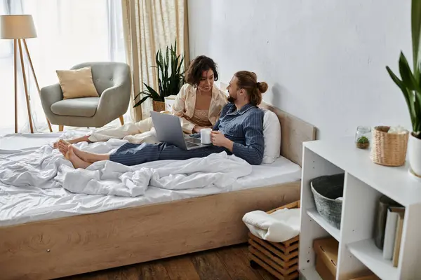 A loving couple spends a relaxing morning in bed, enjoying each others company and a laptop. — Stock Photo