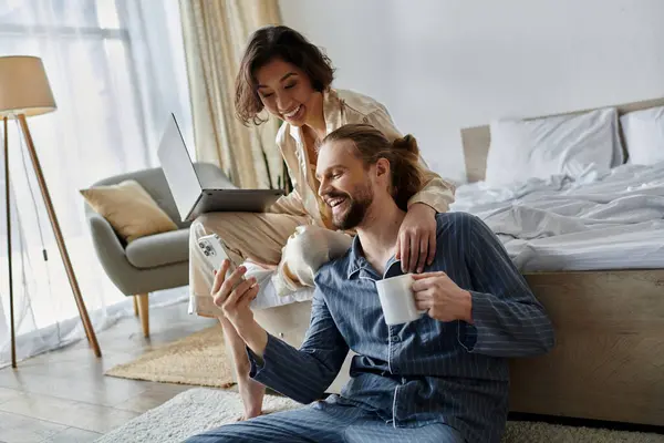 A loving couple relaxes at home, sharing a cup of coffee and a laptop. — Stock Photo