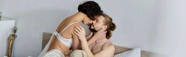 A loving couple sitting closely on a bed, embracing, and enjoying each others company. — Stock Photo