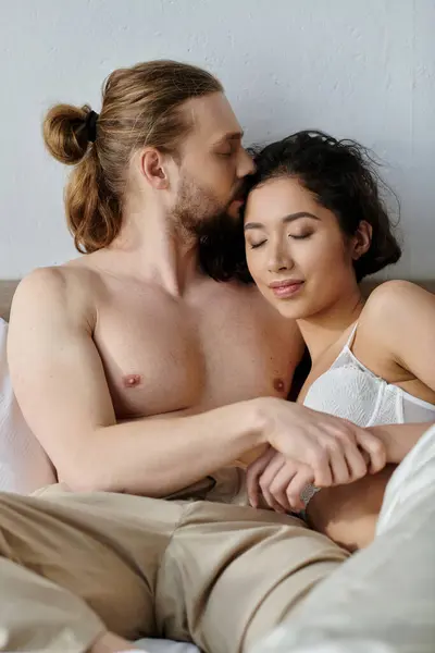 A loving couple shares a tender moment in bed, with the man kissing his partners forehead. — Stock Photo
