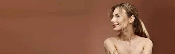 A young woman with vitiligo poses confidently, showcasing a tattoo on her shoulder against a beige background. — Stock Photo