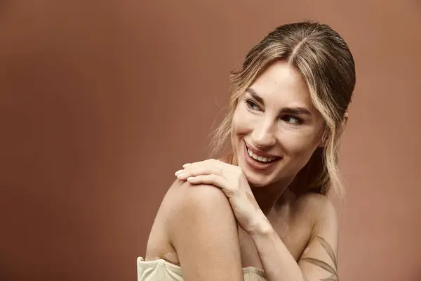 Una giovane donna con la vitiligine posa con un sorriso sicuro, le spalle nude e il tatuaggio in mostra su uno sfondo beige. — Foto stock