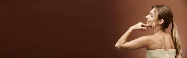 Una giovane donna con la vitiligine si erge con le spalle nude, posando con fiducia su uno sfondo beige. — Foto stock