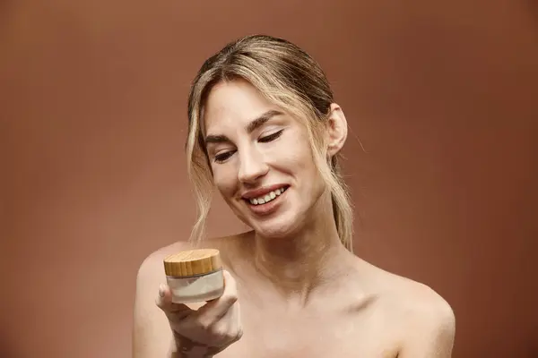 A young woman with vitiligo holds a cream jar, smiling and looking down at it. — Stock Photo