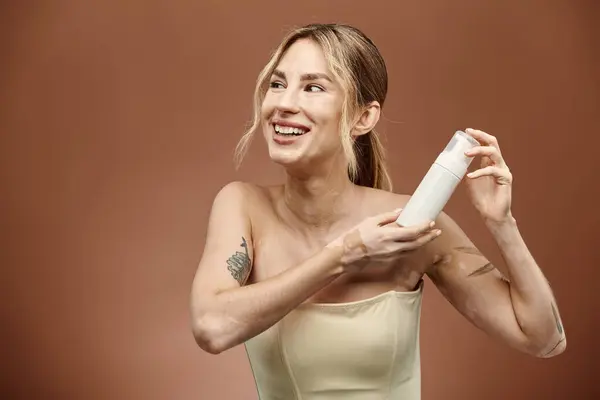A young woman with vitiligo smiles confidently as she holds a skincare product in her hands. — Stock Photo