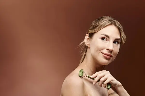 A young woman with vitiligo smiles confidently as she uses a jade roller on her shoulder, highlighting a natural beauty routine. — Stock Photo
