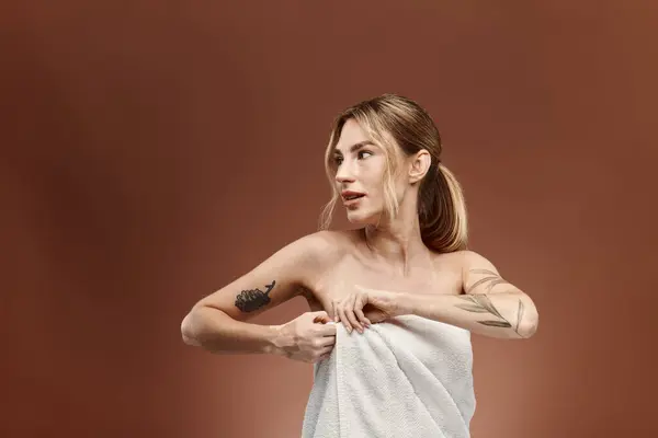 Una giovane donna con la vitiligine si trova in un asciugamano, regolandolo mentre si guarda alle spalle. — Foto stock