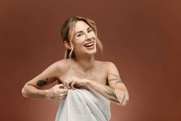 A young woman with vitiligo smiles while wrapping a towel around her shoulders, standing against a beige background. — Stock Photo