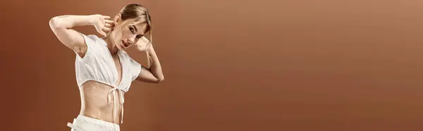 A young woman with vitiligo in a white top and pants poses against a beige background, showcasing her unique beauty in summer fashion. — Stock Photo