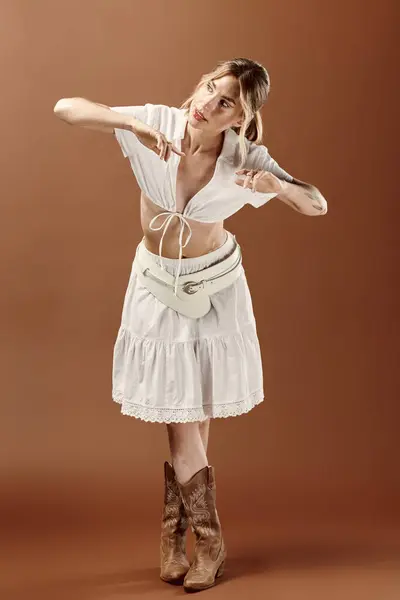 Young woman with vitiligo in white summer ensemble and cowboy boots striking a pose against a beige backdrop. — Stock Photo