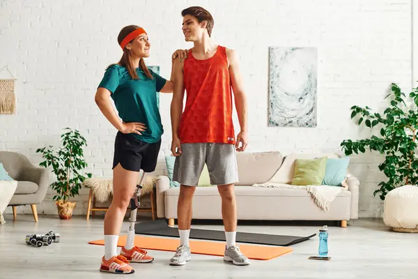 A woman with a prosthetic leg and her boyfriend working out together in their home. — Stock Photo