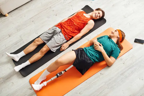 Woman with prosthetic leg enjoys yoga with boyfriend, both smiling. — Stock Photo