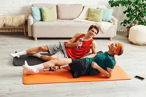 A couple relaxes on yoga mats after a workout session in their living room. — Stock Photo