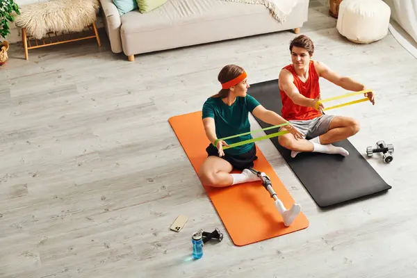 Une femme avec une jambe prothétique travaille avec des bandes de résistance aux côtés de son petit ami. — Photo de stock