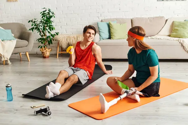 Man and woman on yoga mat, one with resistance band, other with prosthetic leg. — Stock Photo