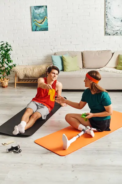 A woman with a prosthetic leg and her boyfriend exercise together at home. — Stock Photo