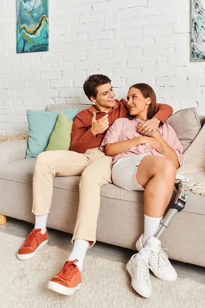 A young couple sits on a couch, laughing and enjoying each others company. — Stock Photo