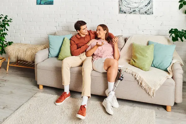 A couple on a couch, woman with prosthetic leg, sharing intimate conversation. — Stock Photo