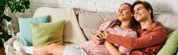 A young couple, including a woman with a prosthetic leg, sits on a couch in a living room. — Stock Photo