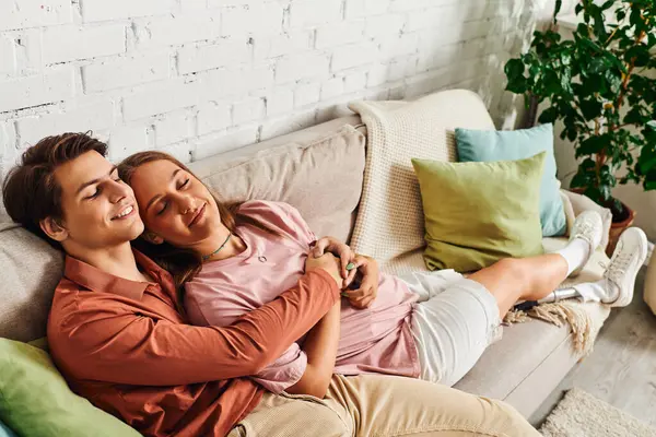 Una pareja se relaja en un sofá, con la mujer apoyando la cabeza sobre el hombro de sus novios. - foto de stock