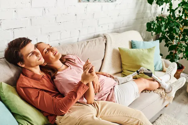 Mujer con prótesis en la pierna se relaja en el sofá con su novio. - foto de stock