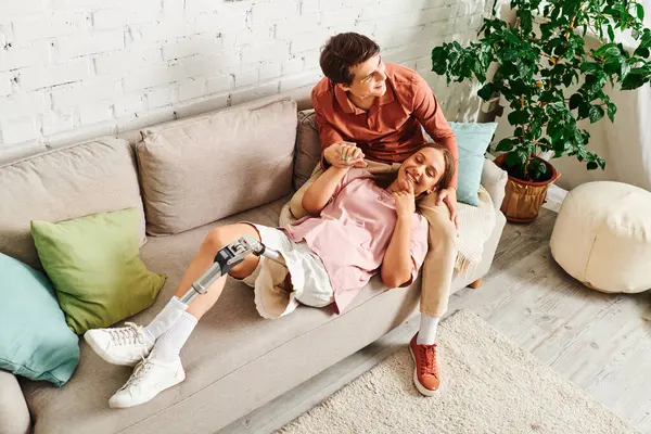 A woman with a prosthetic leg rests comfortably on the couch with her boyfriend. — Stock Photo