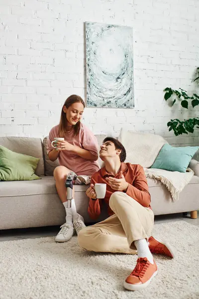 Woman with prosthetic leg and boyfriend enjoy coffee on couch. — Stock Photo