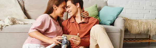 A woman with a prosthetic leg and her boyfriend share a tender moment on a living room floor. — Stock Photo