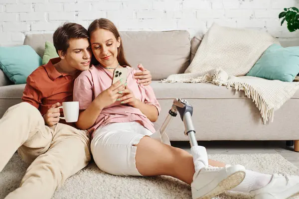 Mujer con prótesis en la pierna disfruta del café con su novio, mirando el teléfono. - foto de stock