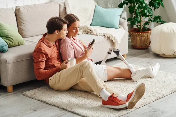 A woman with a prosthetic leg and her boyfriend relax on the floor, enjoying each others company. — Stock Photo